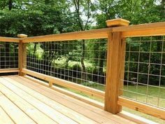 a wooden deck with metal railings and trees in the background