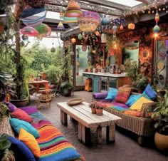 an outdoor living area with lots of colorful pillows and plants on the table, couches and tables