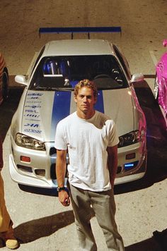 a man standing next to a parked car in front of another person on the street