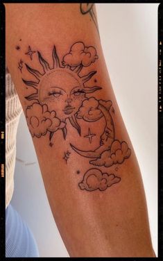 a sun and moon tattoo on the left arm, with clouds in the foreground