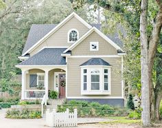 a gray house with white picket fence and trees