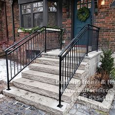 a set of stairs leading up to the front door of a brick house with black railings