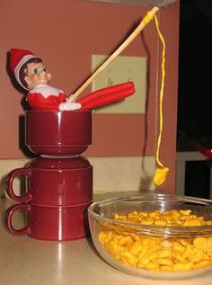 the elf is sitting on top of two cups with cereal in them and a spoon sticking out of it