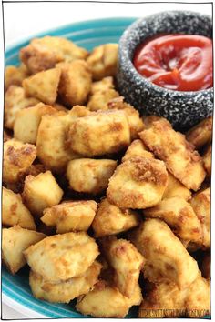 some fried food on a blue plate next to a small bowl with ketchup