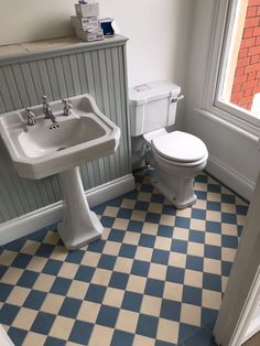 a white toilet sitting next to a bathroom sink in a room with blue and white tiles