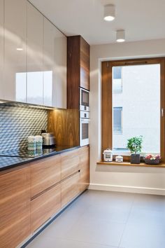 a kitchen with wooden cabinets and white tile flooring next to a window that has a potted plant on it