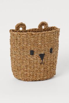 a woven basket with a bear face on the front and black eyes painted on it