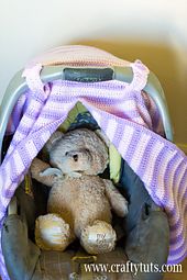 a teddy bear sitting in a car seat under a blanket