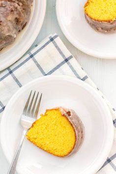 a piece of cake on a white plate with a fork next to it and another slice in the background