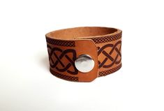 "Celtic Wolf Leather Cuff Bracelet This full grain cowhide leather bracelet is laser engraved with our original Celtic wolf design. The wolf is one of the most prevalent animals in the lore of many cultures. For the Celts the wolf was the companion and/or form many different gods and goddesses and was closely associated with the winter months the Gaelic word for January, \"Faoilleach\" translates to -month of the wolf. *To measure the right size for your wrist we recommend using a measuring tape Engraved Brown Leather Bracelet, Brown Engraved Leather Bracelet, Brown Engraved Leather Cuff Bracelet, Engraved Brown Cuff Bracelets, Brown Leather Engraved Cuff Bracelet, Stamped Leather Cuff Bracelet Gift, Adjustable Viking Leather Bracelet, Adjustable Leather Viking Bracelet, Stamped Leather Cuff Bracelet