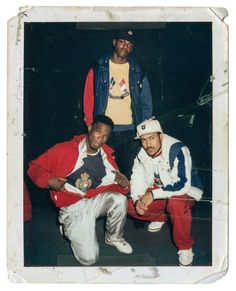 three young men posing for a photo in front of a black background, one is wearing a red and white jacket