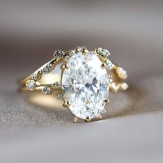 a close up view of a ring with an oval cut diamond in the center and two smaller round diamonds on each side