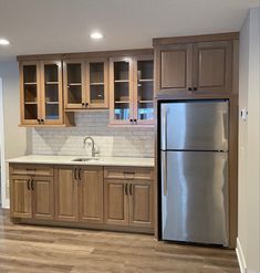 an empty kitchen with wooden cabinets and stainless steel refrigerator freezer combo in the center