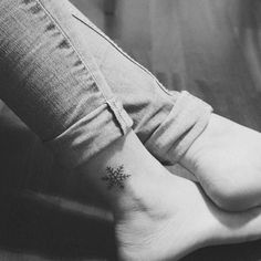 a woman's foot with a small snowflake tattoo on her left ankle