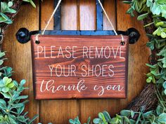 a wooden sign hanging on the side of a door that says please remove your shoes thank you