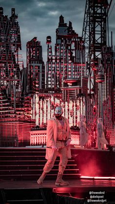 a man standing on top of a stage in front of a large cityscape