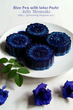 blue pea with lotus pake jelly mooncakes on a white plate surrounded by purple flowers