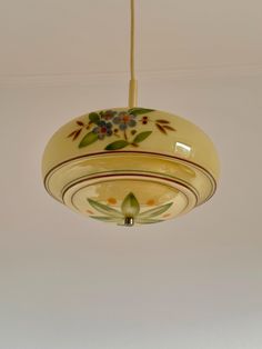 a light that is hanging from the ceiling with flowers painted on it's side