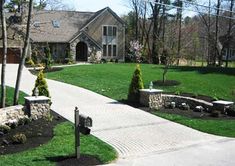 a house with landscaping in front of it and trees on the side of the road