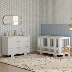 a baby's room with blue and white wallpaper, a dresser and crib