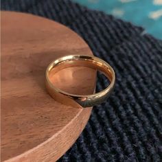 a gold wedding ring sitting on top of a wooden table next to a blue rug