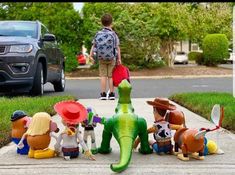 a group of toy figurines sitting on the sidewalk in front of a car