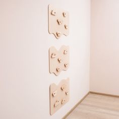 three wooden pegs are mounted to the wall in an empty room with wood flooring