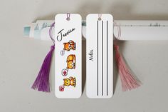 two bookmarks with tassels attached to each other on a white surface next to a crayon ruler