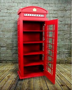 a red phone booth sitting on top of a wooden floor next to a brick wall