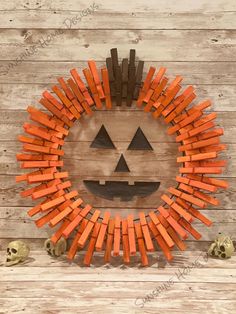 a pumpkin wreath made out of orange sticks and bones on a wooden background with skulls