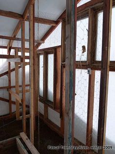 an unfinished room with chicken wire on the walls and windows in it, along with wood framing