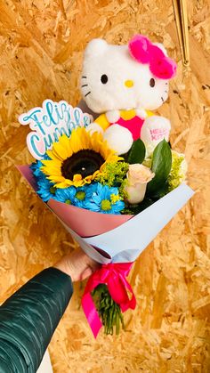 a hello kitty bouquet with sunflowers, roses and a teddy bear in it