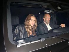 a man and woman sitting in the back of a car