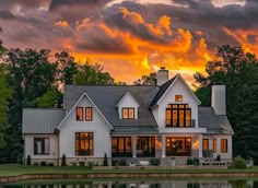 a large white house sitting on top of a lush green field next to a lake