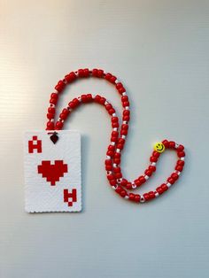 a red beaded necklace with a pacman face on it, next to a card