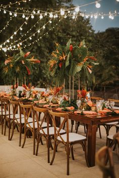 a long wooden table topped with lots of plates and place settings covered in greenery