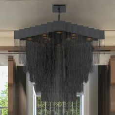 a large chandelier hanging from the ceiling in a room with windows and curtains