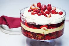 a dessert with strawberries and whipped cream in a glass dish on a white table