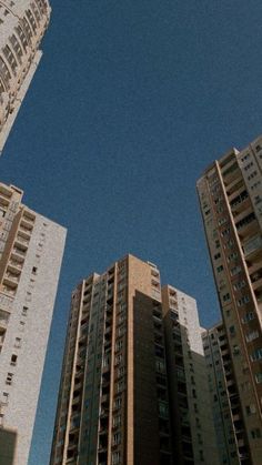 two tall buildings with windows and balconies against a blue sky