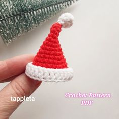 a crocheted santa hat sitting on top of a white table next to a christmas tree