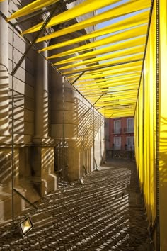 the inside of a building that is covered in yellow pipes and metal gratework