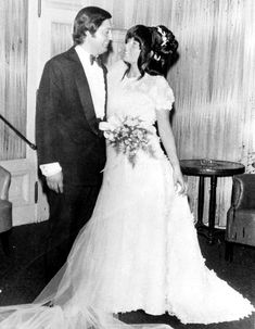 an old black and white photo of a bride and groom kissing each other in the living room