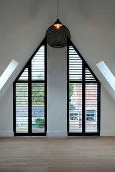 an empty room with two large windows in the ceiling and wooden floors on both sides