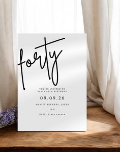 a white card with the word forty printed on it next to some lavenders in front of a window