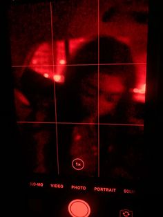 a person's face is seen through a red light in front of the camera