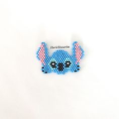 a blue beaded stitched brooch sitting on top of a white surface