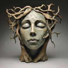 a sculpture of a woman's face with branches on her head and eyes closed