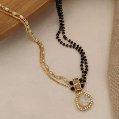 a black and white beaded necklace next to a piece of cloth on a table