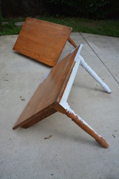 an upside down wooden table sitting on top of a cement floor next to a white pipe