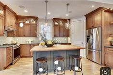 a large kitchen with wooden cabinets and stainless steel appliances, along with two bar stools